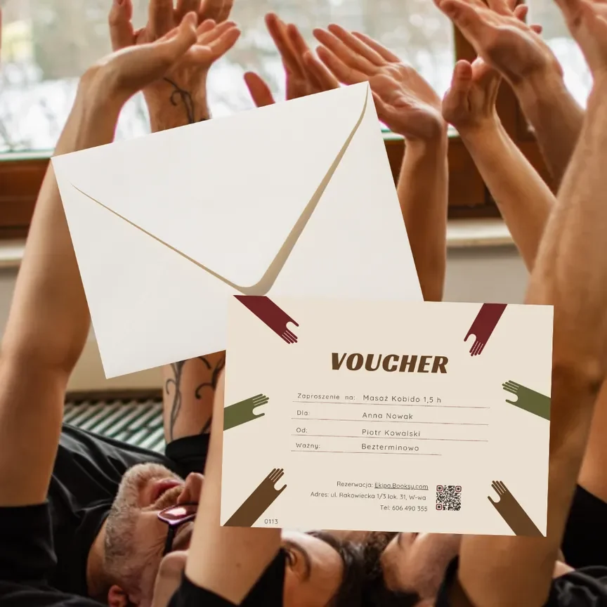 Voucher na masaż Kobido trzymany przed grupą ludzi z podniesionymi dłońmi w geście radości